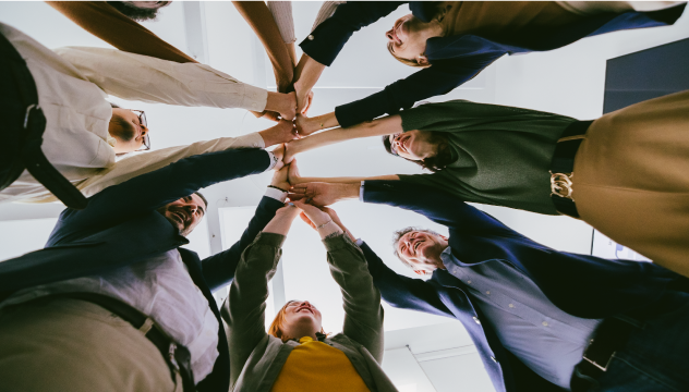 Group of people standing in circle bringing hands together in centre
