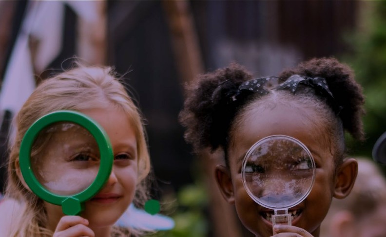 Young girls looking through magnifying glasses