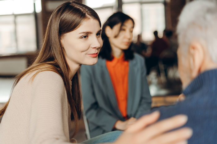 Woman sitting in a group with hand on shoulder of person beside her